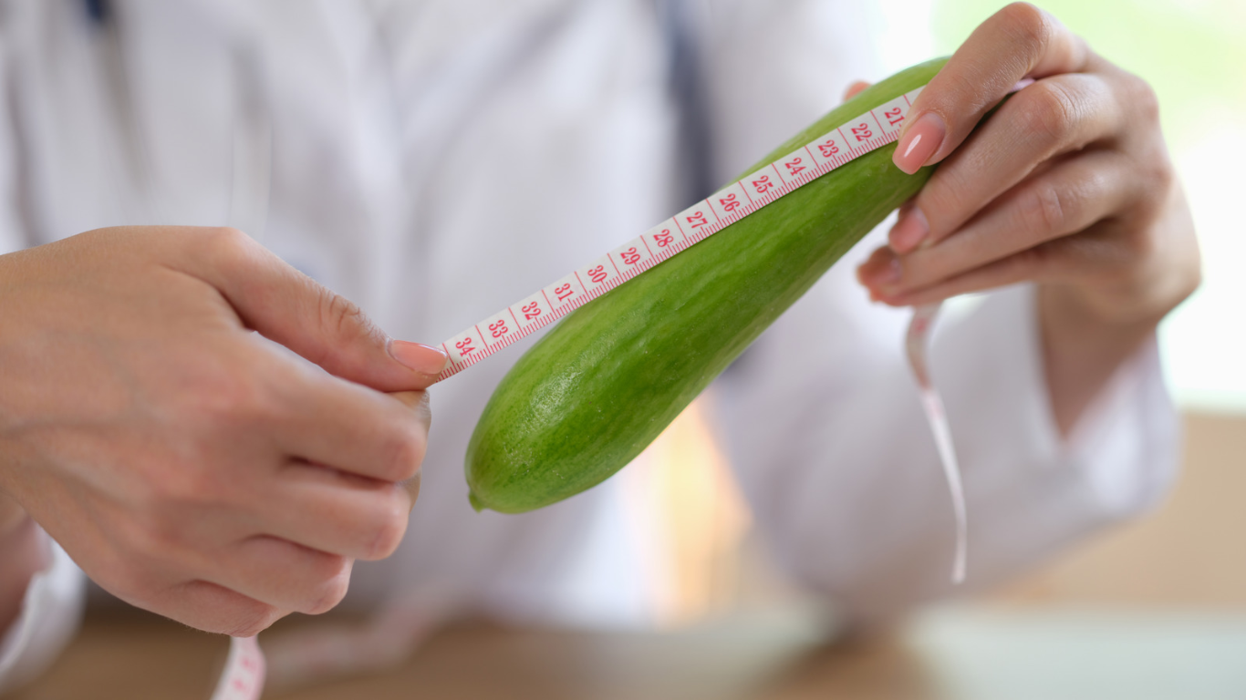 person measuring a courgette or zucchini with a measuring tape