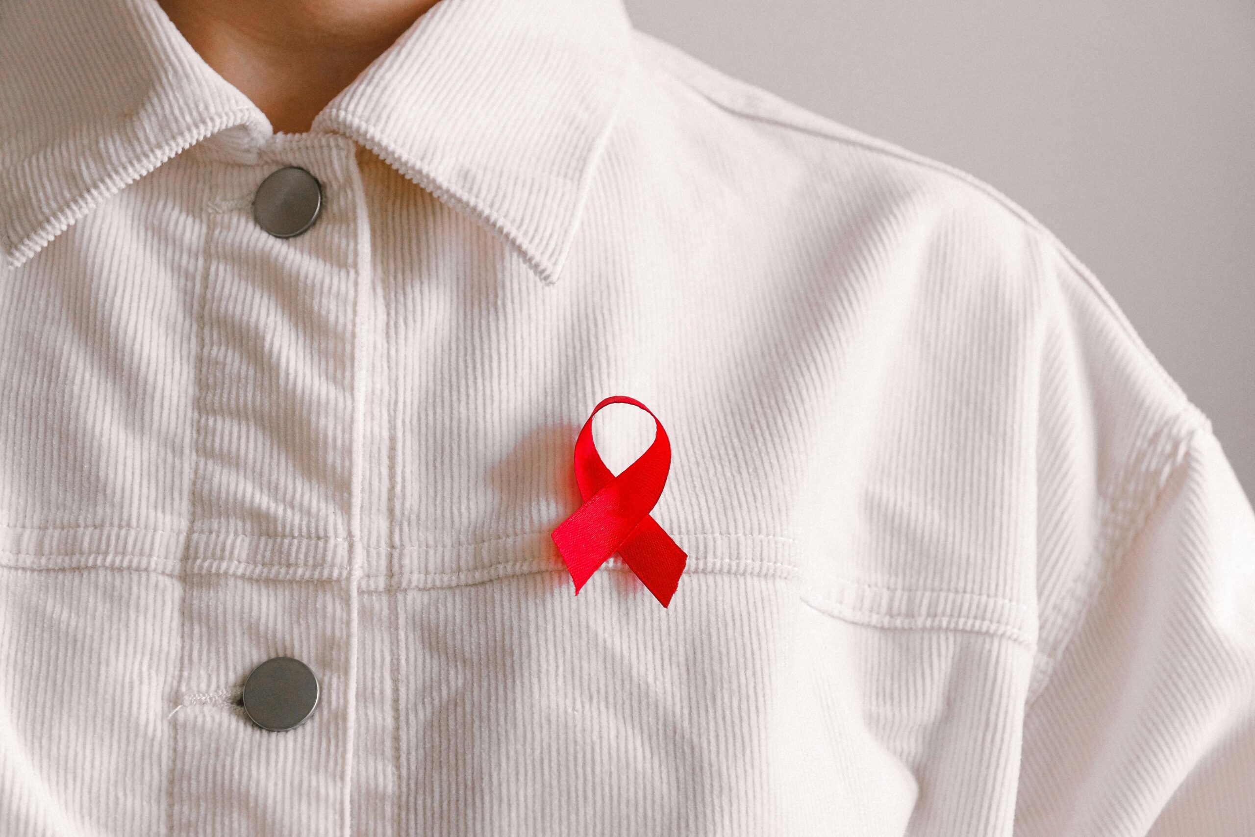 red aids ribbon attached to a white polo