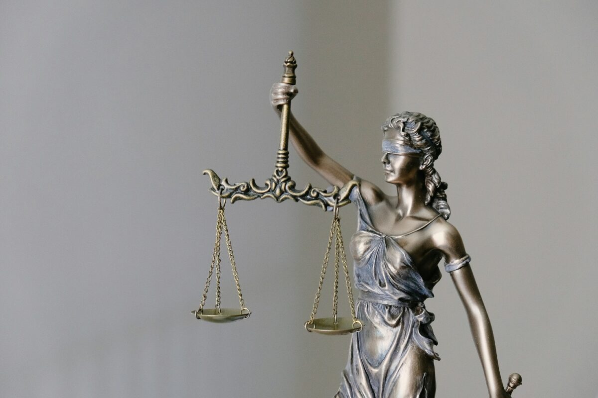 Statue of Lady Justice holding balanced scales and a sword, symbolizing fairness and impartiality in the legal system, with a neutral background.