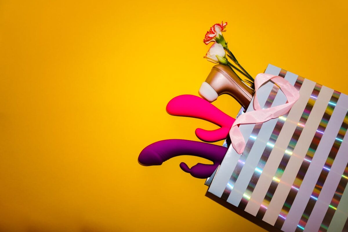 A shopping bag with adult toys, flowers, and a high heel shoe on a vibrant yellow background.