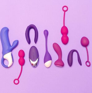 Assorted silicone female sex toys including vibrators and kegel balls arranged on a purple background