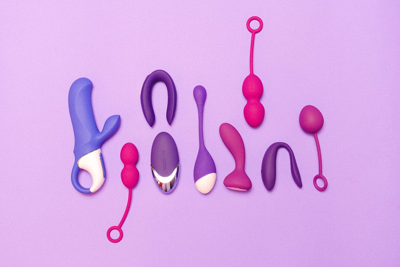 Assorted silicone female sex toys including vibrators and kegel balls arranged on a purple background