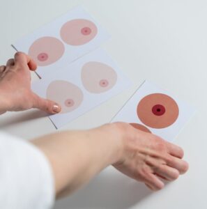 Hands sorting illustration cards showing diverse breast and nipple shapes for body awareness and health education