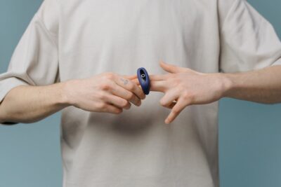 A man removing a cock ring from his finger, simulating a penis.