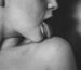 A black and white photo capturing a person’s tongue sensually touching a shoulder, expressing intimacy and erotic tension.