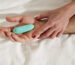 Teal bullet vibrator resting on a partner's palm, perfect for intimate shared moments in bed.