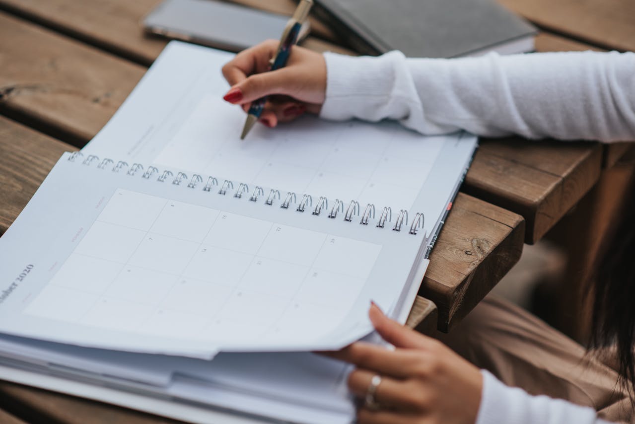 Someone writing in a planner. Planning the next meeting is a crucial step in surviving an LDR Philippines and staying motivated.