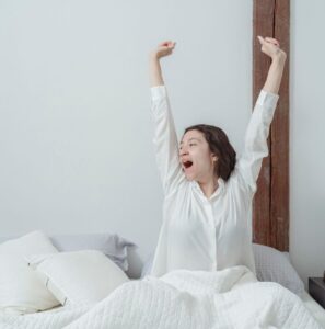 Woman stretching happily after waking up, symbolizing the confidence and energy that come from good intimate self care and daily wellness habits.