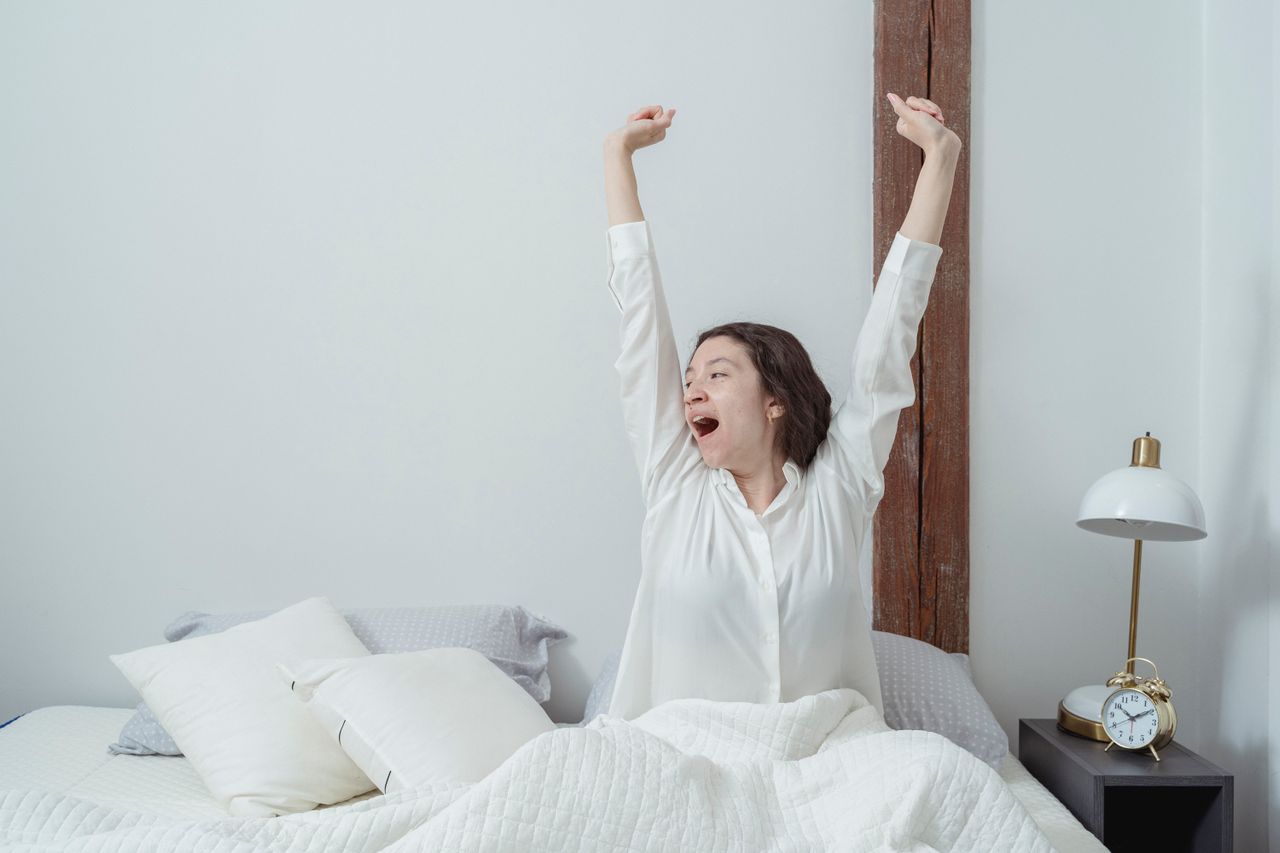 Woman stretching happily after waking up, symbolizing the confidence and energy that come from good intimate self care and daily wellness habits.