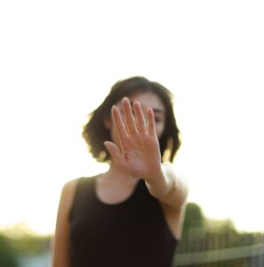 A woman holds her hand out in a stop gesture, symbolizing protection against harassment under the Safe Spaces Act or Bawal Bastos Law.